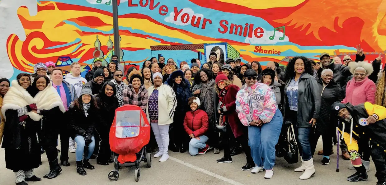 Community posed in front of mural
